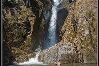 Person swimming at the bottom of a waterfall