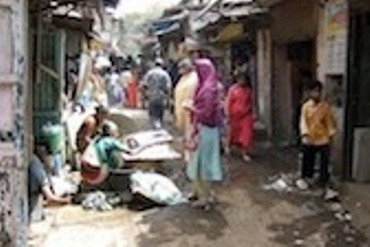 Women and children walk around a narrow laneway