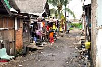 Homes on a narrow dirt street with washing hanging out the front and small children playing by the doorstep