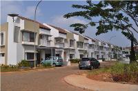 A row of town houses on a tree-lined street in suburban Jakarta.
