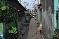 A narrow back street in Bali, lined with porches with clothing hanging overhead.