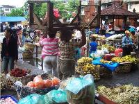 Two women produce sellers balance a table on their head in an Indonesian pasar (marketplace).