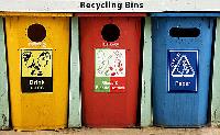Three recycling bins lined up next to each other for drink cans, glass and plastic and paper