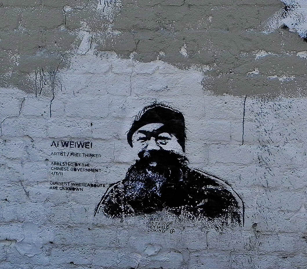 A portrait of artist Ai Wei Wei painted on a brick wall
