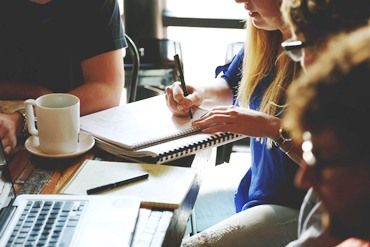 A group of teachers sit at a desk and engage in discussion